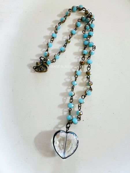 Necklace with heart-shaped pendant and turquoise beads on a white background
