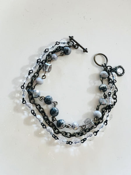 Multistrand bracelet with beads and chain links on a light background