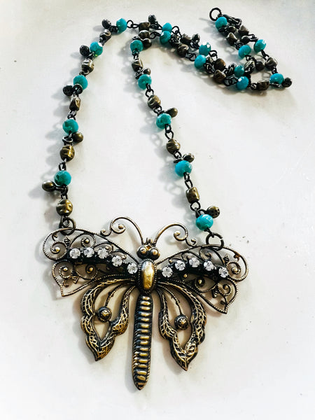 Butterfly-shaped pendant necklace with turquoise beads on a white background