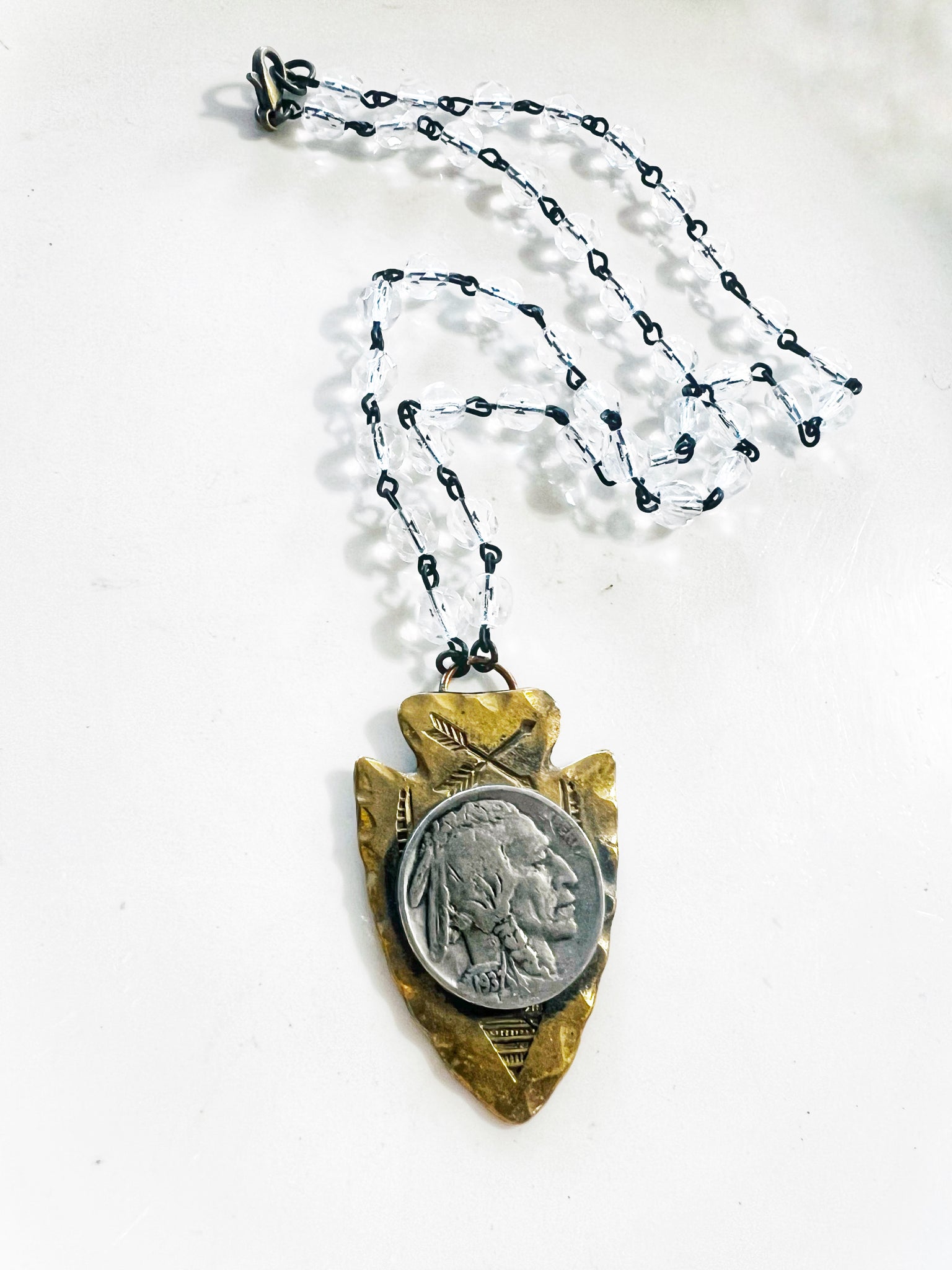 Necklace with arrowhead pendant featuring a coin on a white background