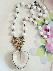 Necklace with heart-shaped pendant and white beads on a floral background