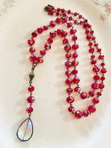Necklace with red beads and a teardrop-shaped pendant on a light background