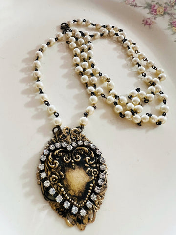 Pearl necklace with an ornate pendant on a floral-patterned surface