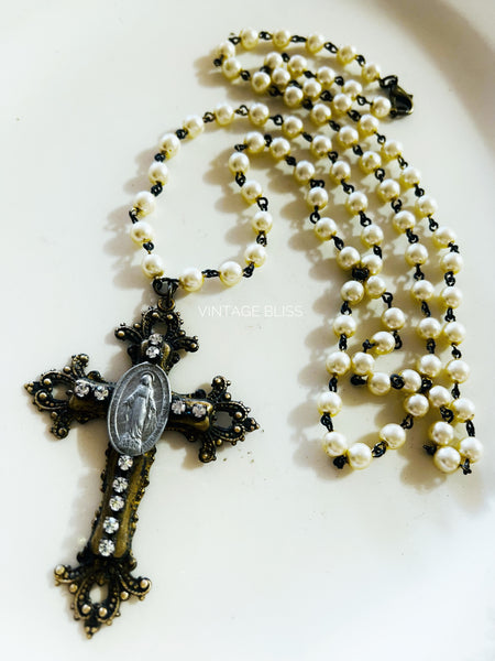 Pearl rosary with black accents and a cross on a white background