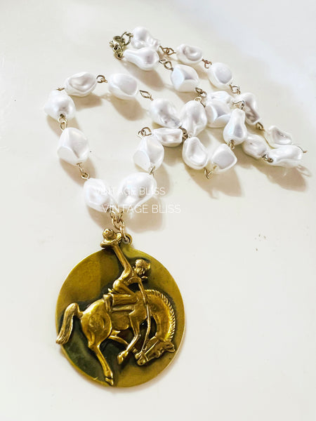 Necklace with gold pendant and white beads on a light background
