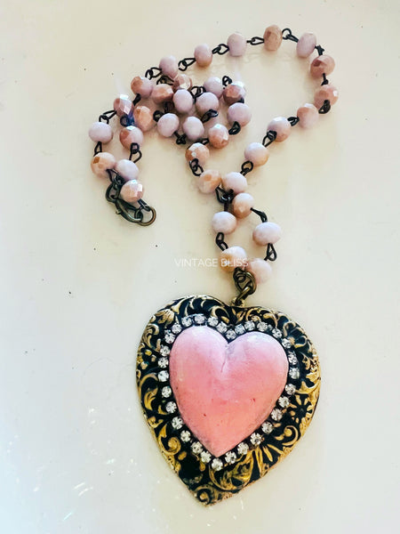 Necklace with pink heart pendant and beaded chain on a light background