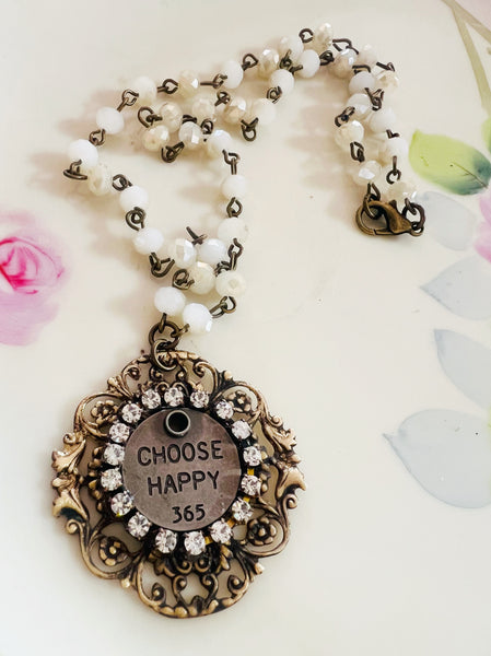 Necklace with a pendant that says 'Choose Happy 365' on a light background