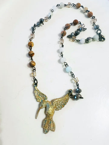 Necklace with a hummingbird pendant and multicolored beads on a white background