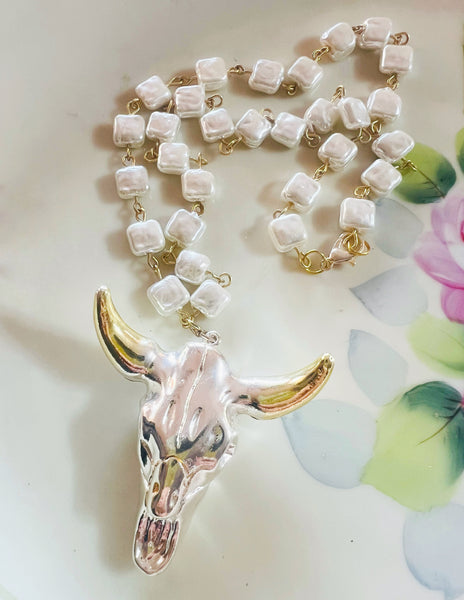 Necklace with cow skull pendant on a floral background
