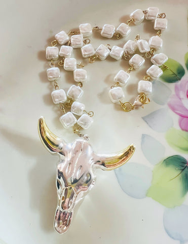 Necklace with cow skull pendant on a floral background