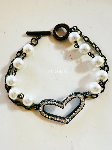 Bracelet with heart-shaped clasp and pearl-like beads on a white background