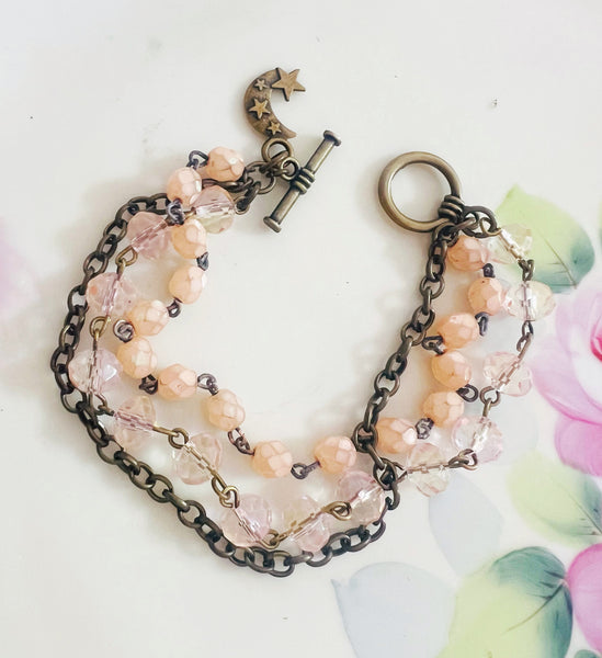 Bracelet with pink beads and chain on a white background