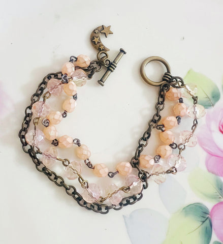 Bracelet with pink beads and chain on a white background