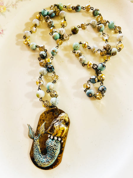 Necklace with mermaid pendant and beaded chain on a light background