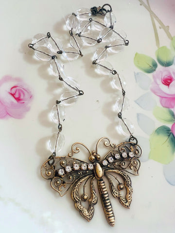 Necklace with butterfly pendant and clear beads on a floral background