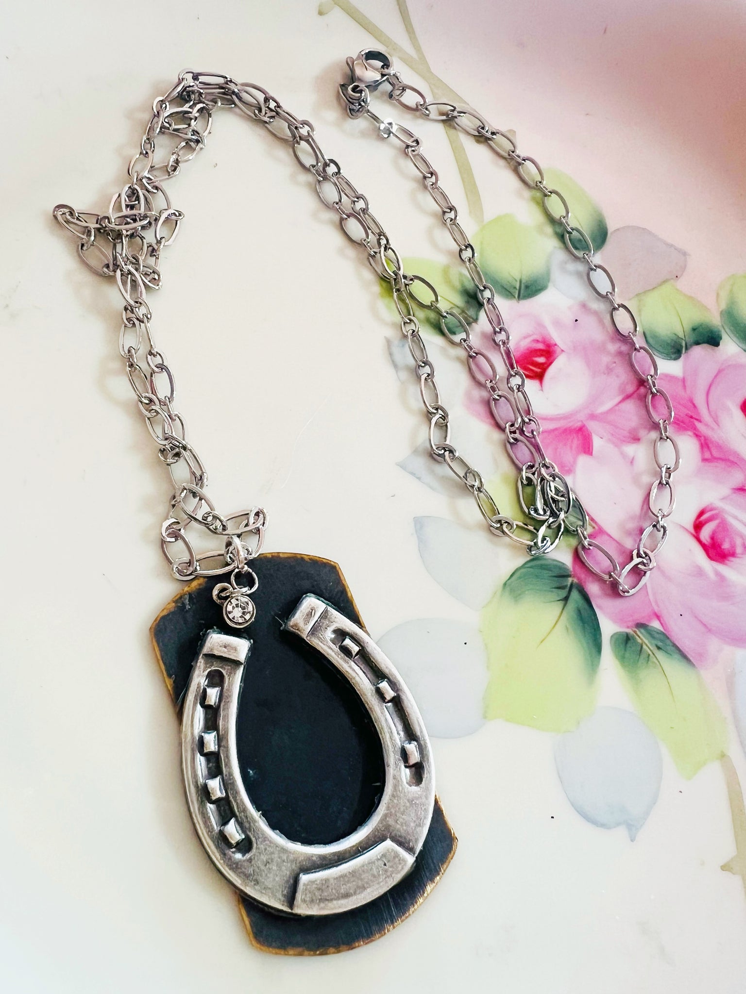 Silver horseshoe pendant necklace on a floral background
