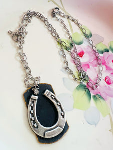 Silver horseshoe pendant necklace on a floral background