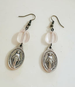 Pair of silver religious earrings with clear beads on a white background