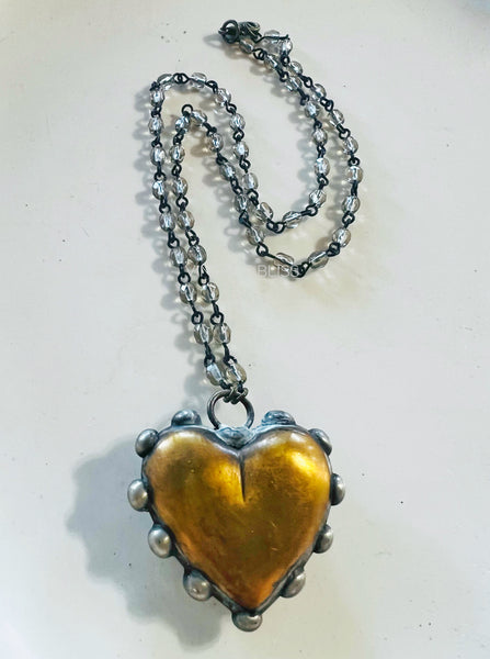 Heart-shaped pendant necklace with a metallic chain on a light background