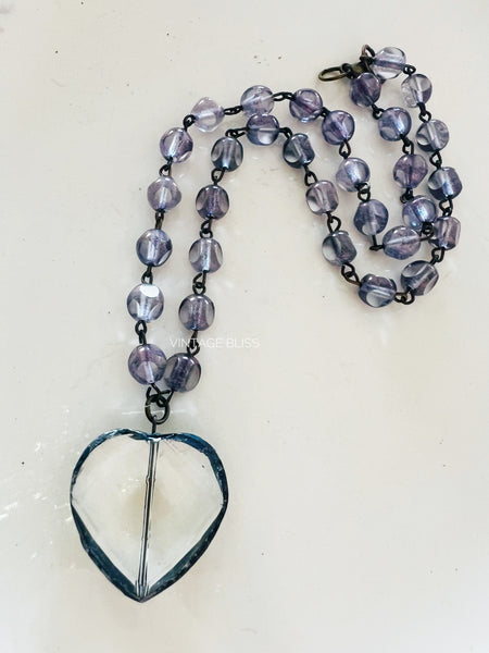 Necklace with heart-shaped pendant and purple beads on a white background