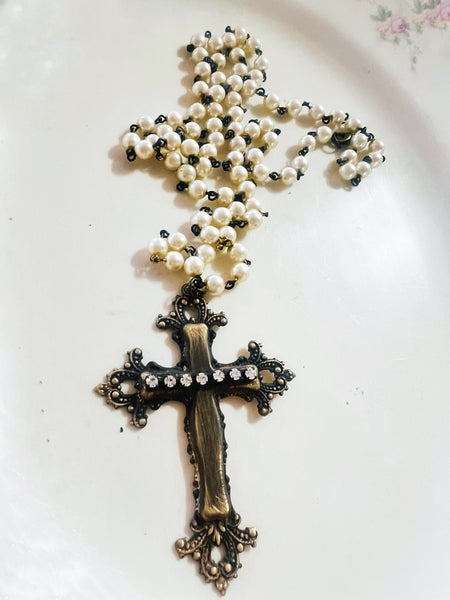 Pearl rosary with a decorative cross on a white surface